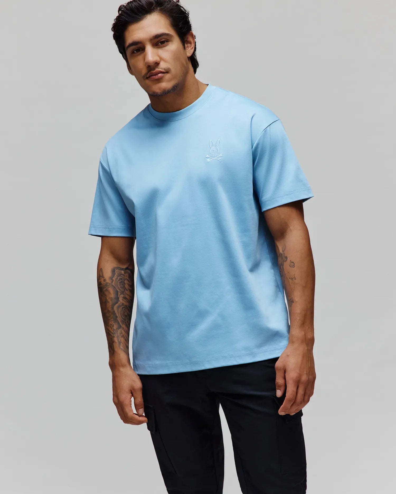 Mens Oscar Oversized Tee in light blue jersey knit, featuring a small tonal embroidered Psycho Bunny skull logo on the left chest for a refined streetwear look.