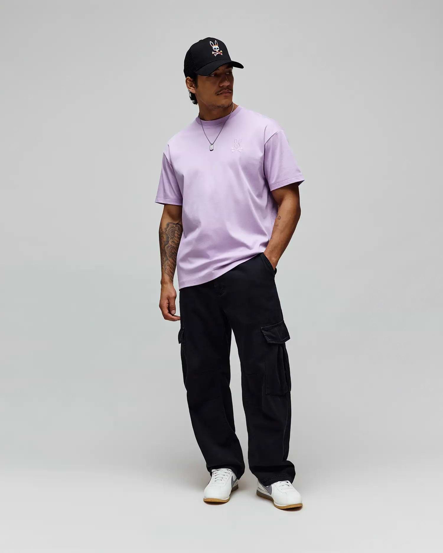 Lavender jersey Mens Oscar Oversized Tee with a white embroidered Psycho Bunny logo on the left chest, black relaxed cargo pants, and a black cap featuring the iconic white-red bunny skull. (3)