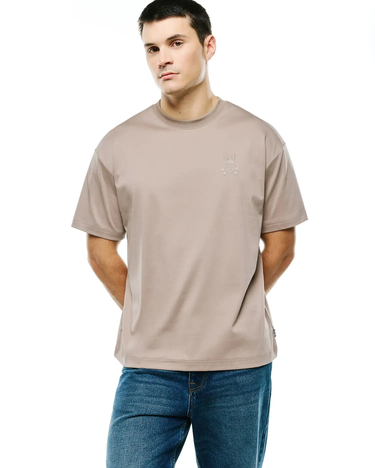 Men's Oscar Oversized Tee in light beige, featuring a tonal embroidered Psycho Bunny skull logo on the left chest and a small woven tag on the side hem, made from smooth jersey fabric. (1)