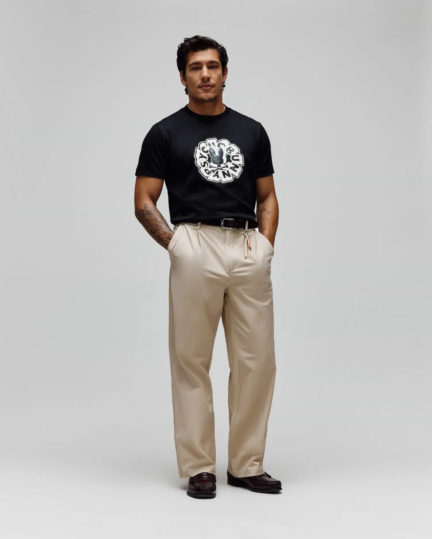 Mens Toby Graphic Tee, a black classic fit jersey t-shirt with a prominent, large circular distressed white and grey Psycho Bunny skull logo graphic on the chest, encircled by text.