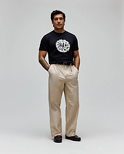 Mens Toby Graphic Tee, a black classic fit jersey t-shirt with a prominent, large circular distressed white and grey Psycho Bunny skull logo graphic on the chest, encircled by text.