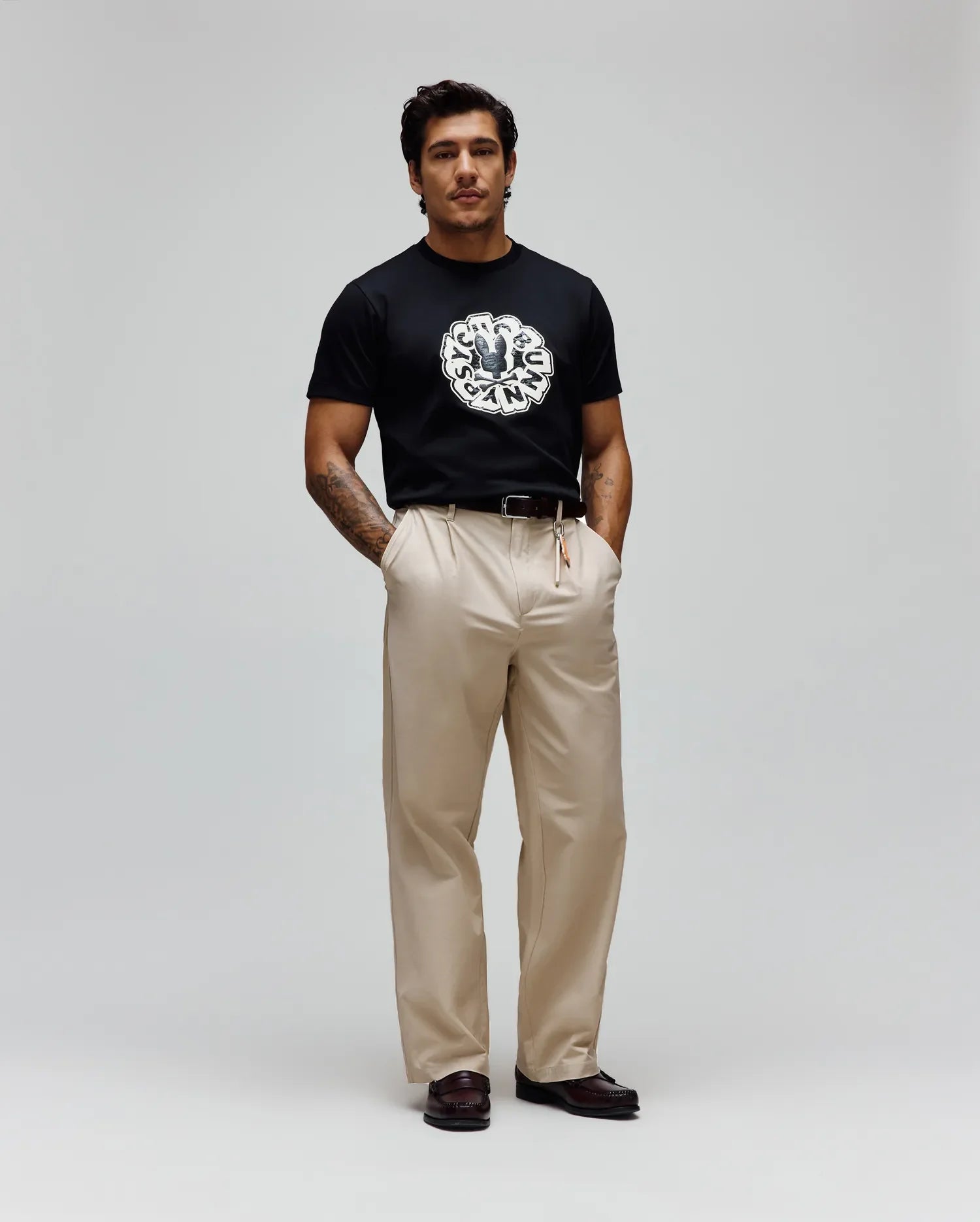 Mens Toby Graphic Tee, a black classic fit jersey t-shirt with a prominent, large circular distressed white and grey Psycho Bunny skull logo graphic on the chest, encircled by text.