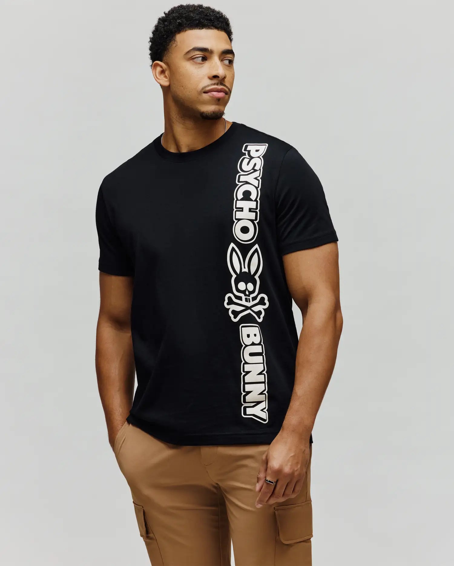 Mens Toby Wordmark Tee, black classic fit jersey knit t-shirt with a large vertical white Psycho Bunny wordmark and bunny skull graphic on the left side. (3)