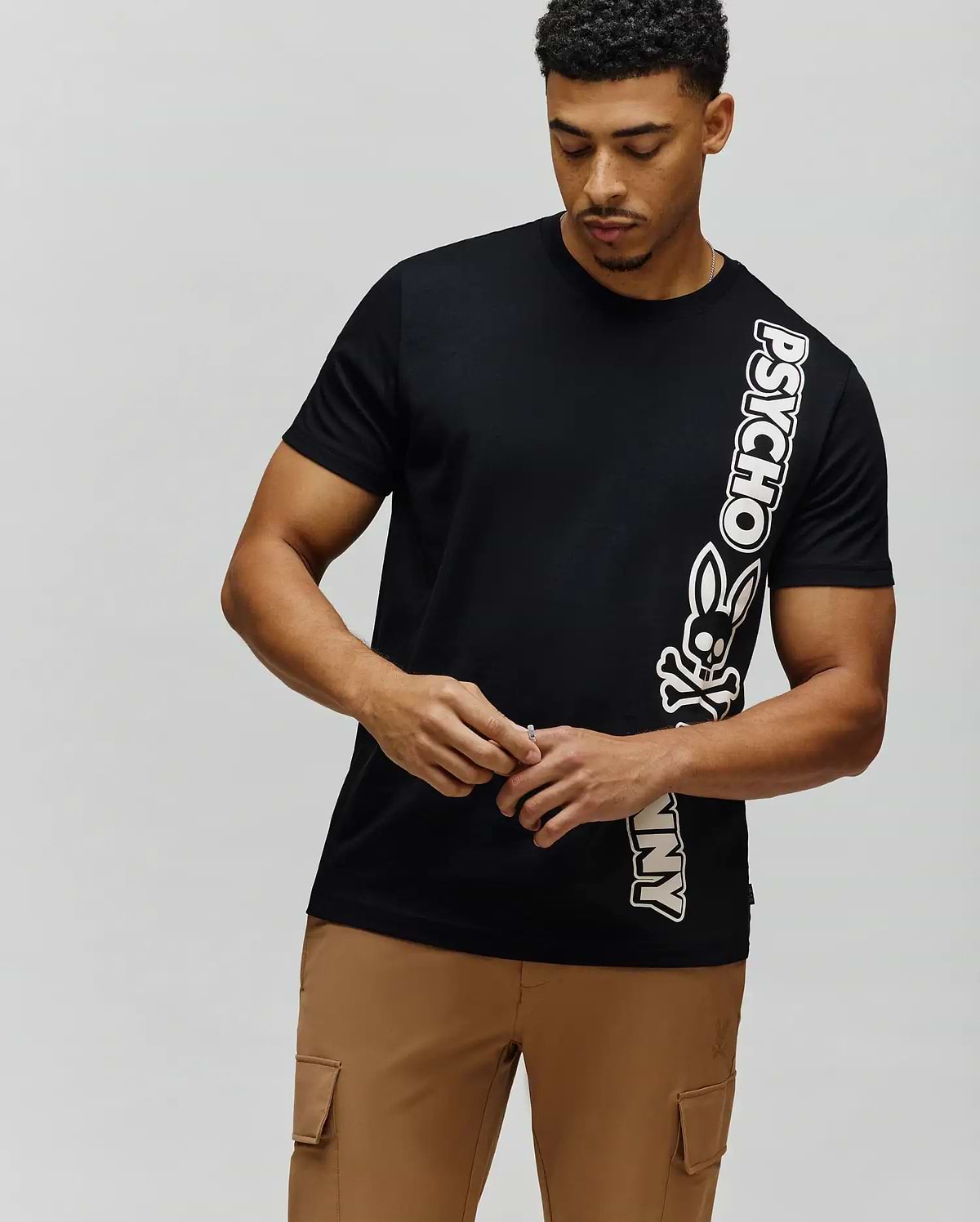 Mens Toby Wordmark Tee, black classic fit jersey t-shirt with a bold vertical white and pink-outlined Psycho Bunny wordmark and skull logo on the right. (1)