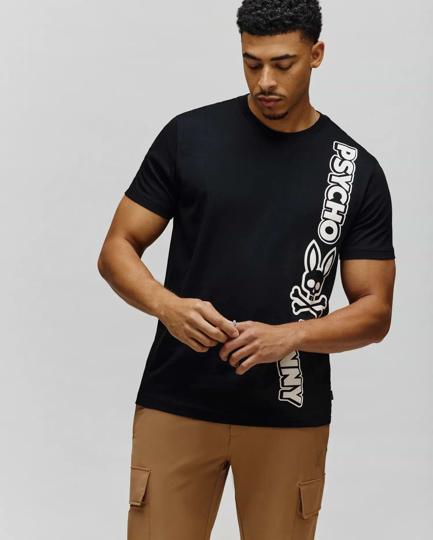 Mens Toby Wordmark Tee, black classic fit jersey t-shirt with a bold vertical white and pink-outlined Psycho Bunny wordmark and skull logo on the right. (1)