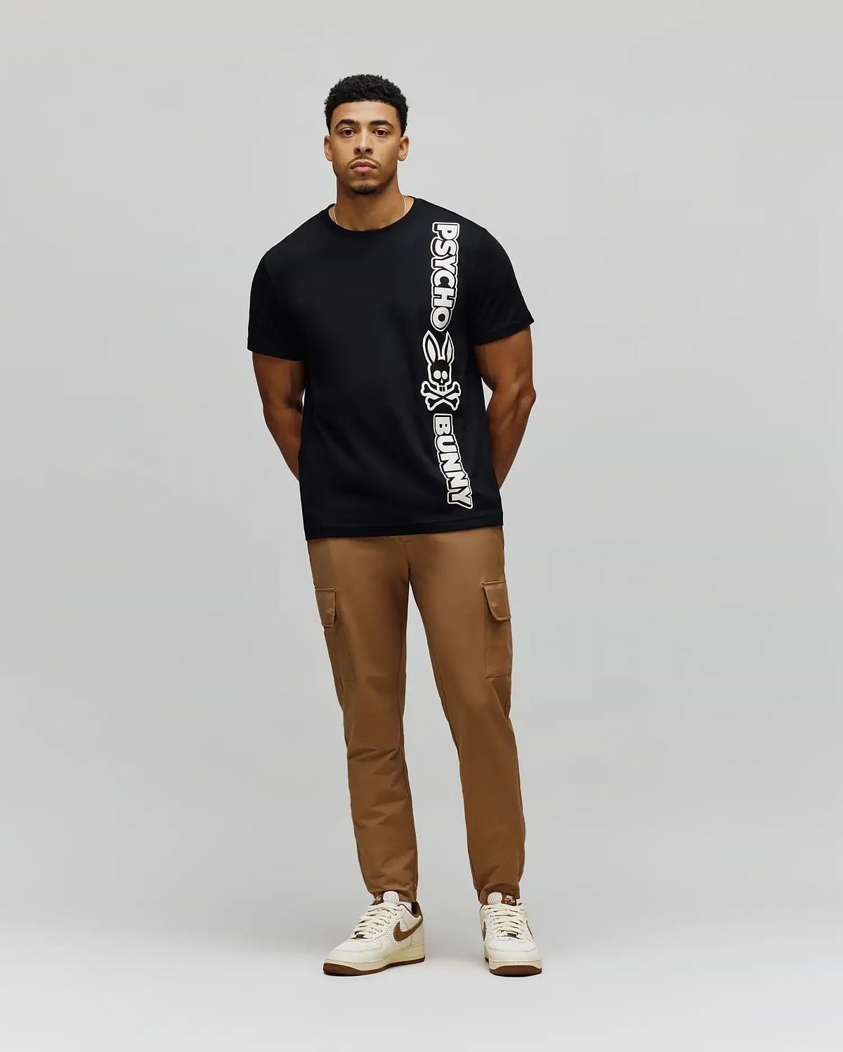Mens Toby Wordmark Tee, a classic fit black jersey t-shirt featuring a large, vertical white Psycho Bunny wordmark and iconic bunny skull logo on the left side. (4)