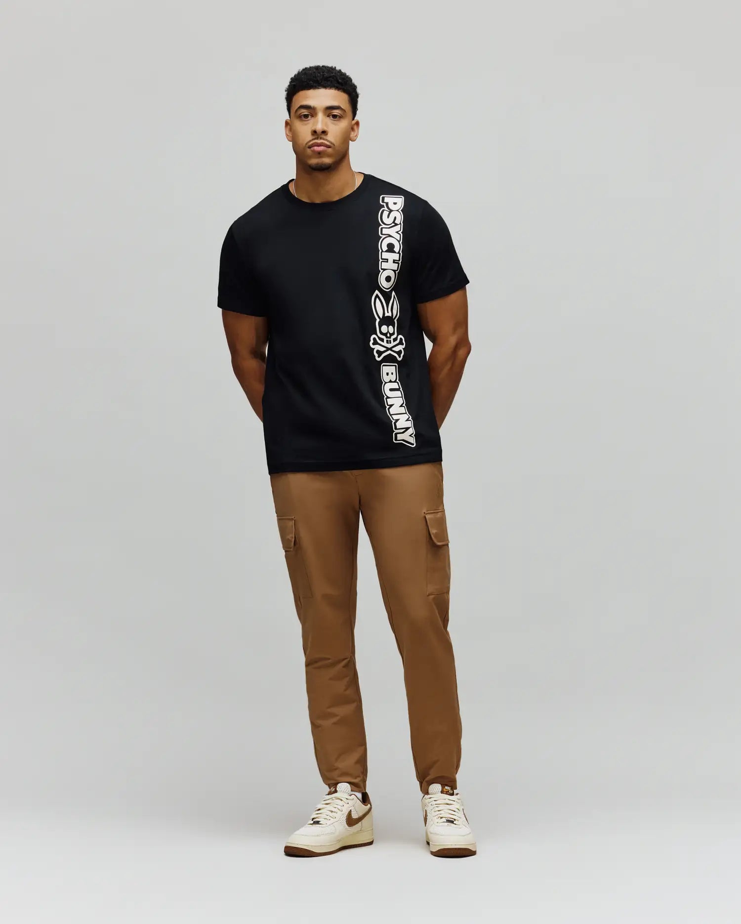 Mens Toby Wordmark Tee, a classic fit black jersey t-shirt featuring a large, vertical white Psycho Bunny wordmark and iconic bunny skull logo on the left side. (4)