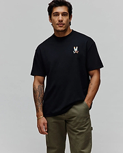 Mens Ara Oversized Tee in black jersey knit, featuring a relaxed fit and a small, vibrant multi-color embroidered Psycho Bunny skull logo on the left chest.
