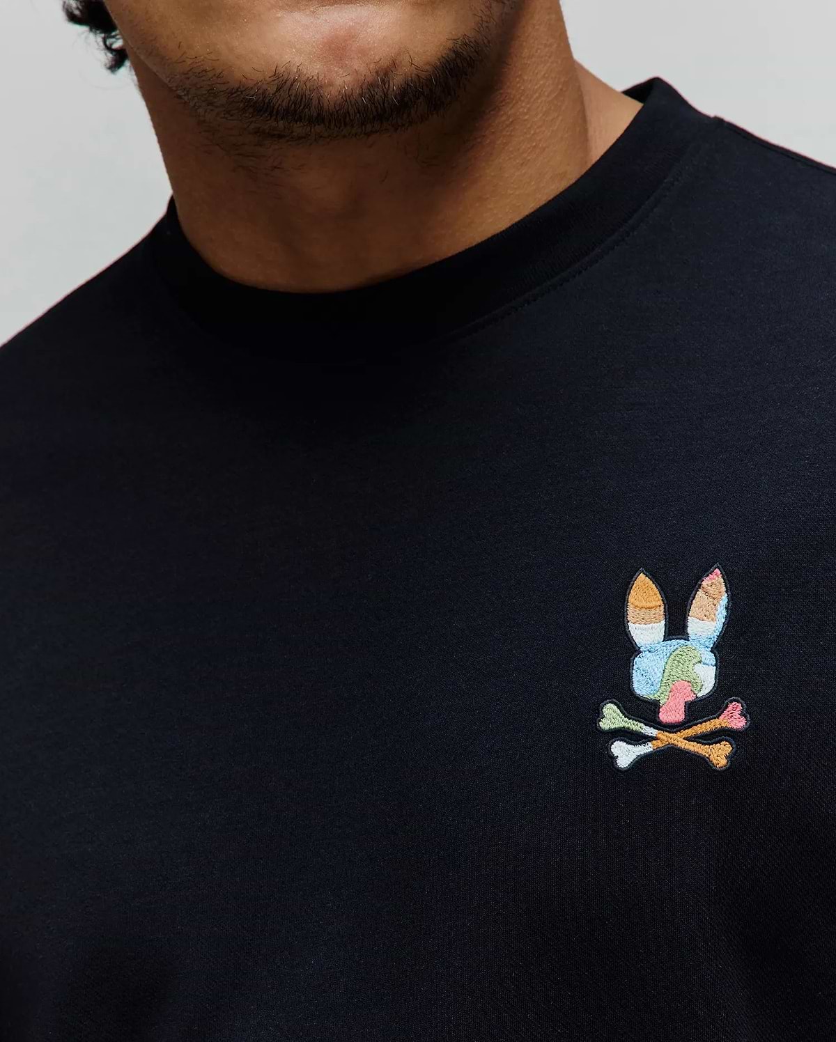 Black Mens Ara Oversized Tee in smooth jersey knit, featuring a small, vibrant multicolor embroidered Psycho Bunny skull logo on the left chest.