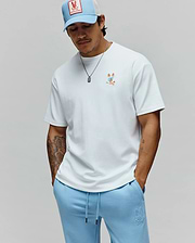 Mens Ara Oversized Tee in white jersey with a small, colorful deconstructed Psycho Bunny logo on the left chest, paired with light blue french terry sweatpants featuring an embroidered tone-on-tone logo on the left thigh. (3)