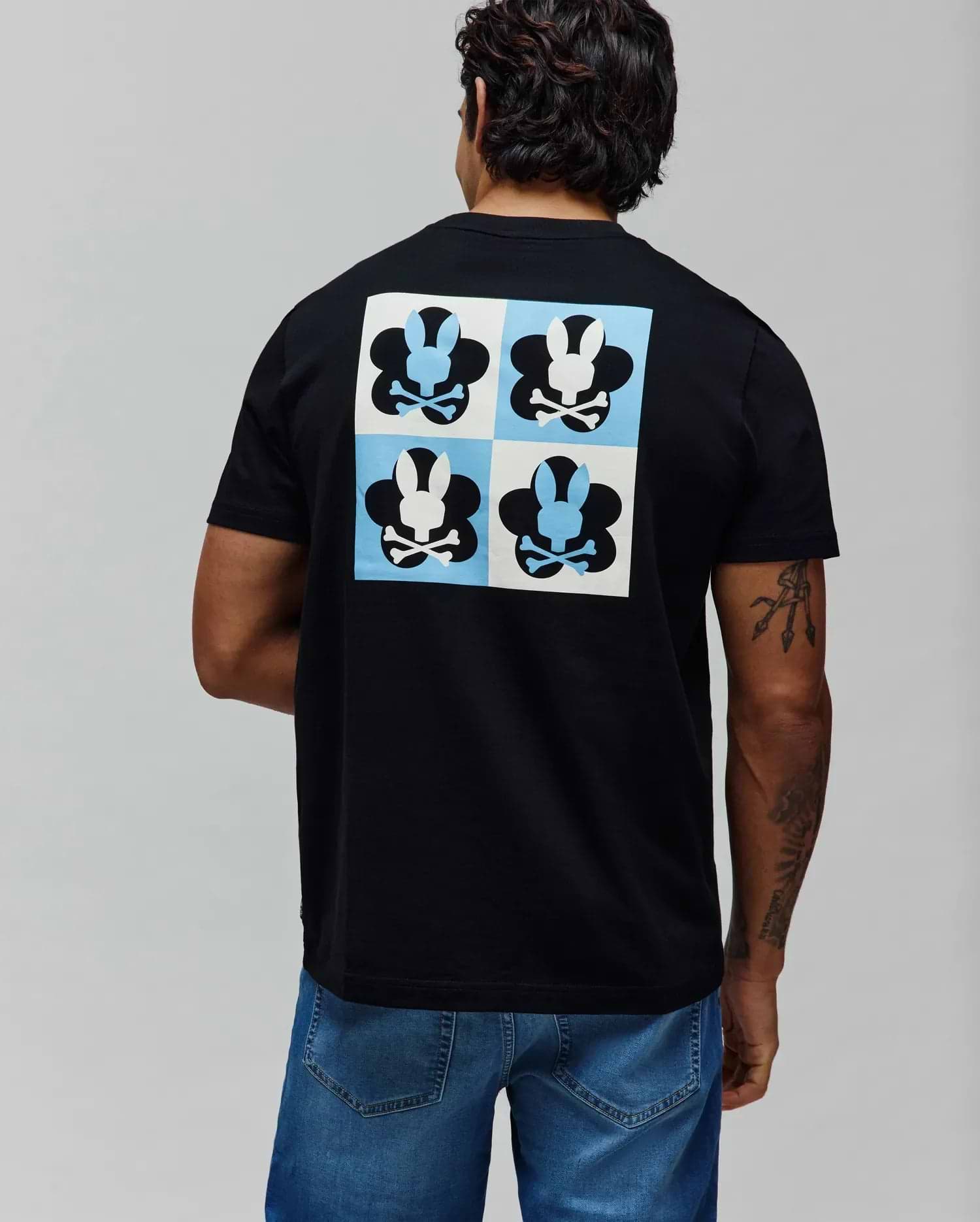 Mens Aiden Back Graphic Tee, black classic fit jersey t-shirt with a large back graphic featuring a checkerboard of light blue and white squares, each containing a black or white Psycho Bunny skull logo. (1)