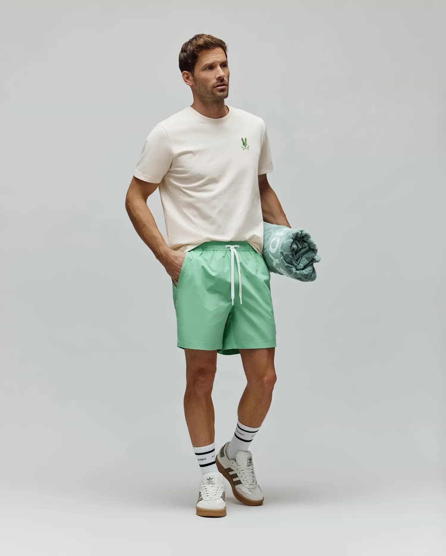 Cream Mens Aiden Back Graphic Tee, a classic fit jersey tee with a small green embroidered Psycho Bunny skull logo on the left chest, styled with relaxed mint green drawstring shorts. (4)