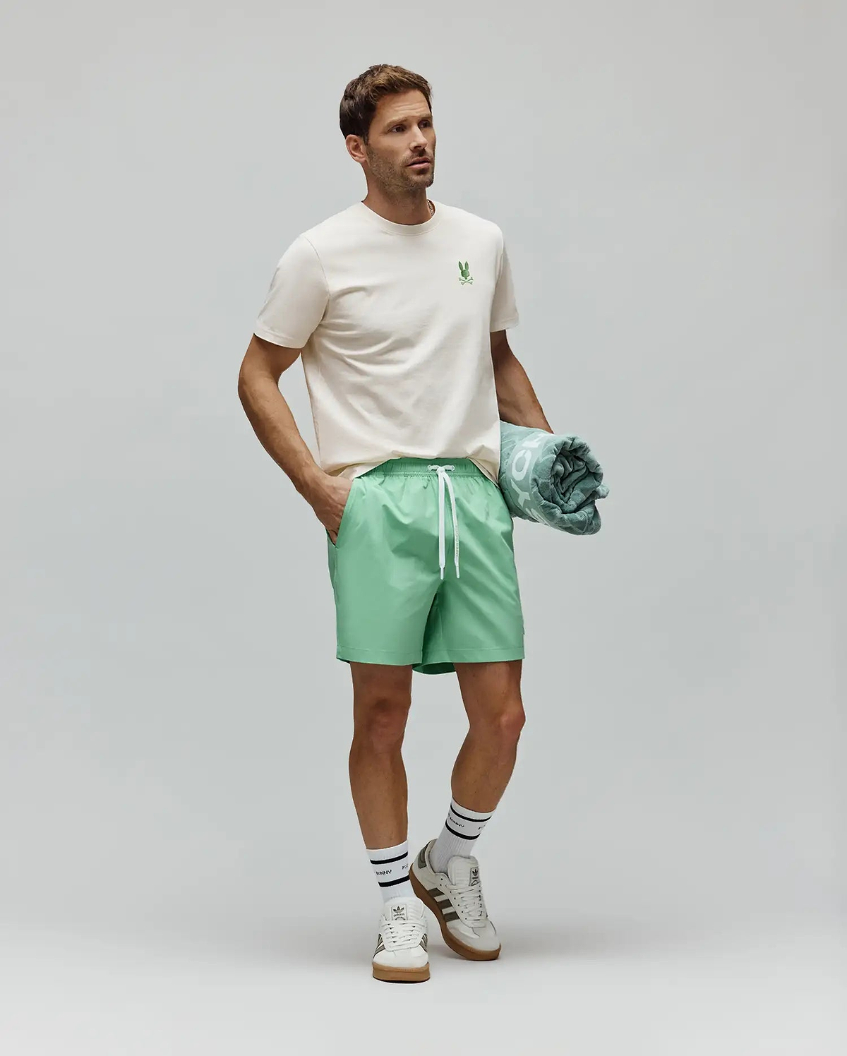 Cream Mens Aiden Back Graphic Tee, a classic fit jersey tee with a small green embroidered Psycho Bunny skull logo on the left chest, styled with relaxed mint green drawstring shorts. (4)