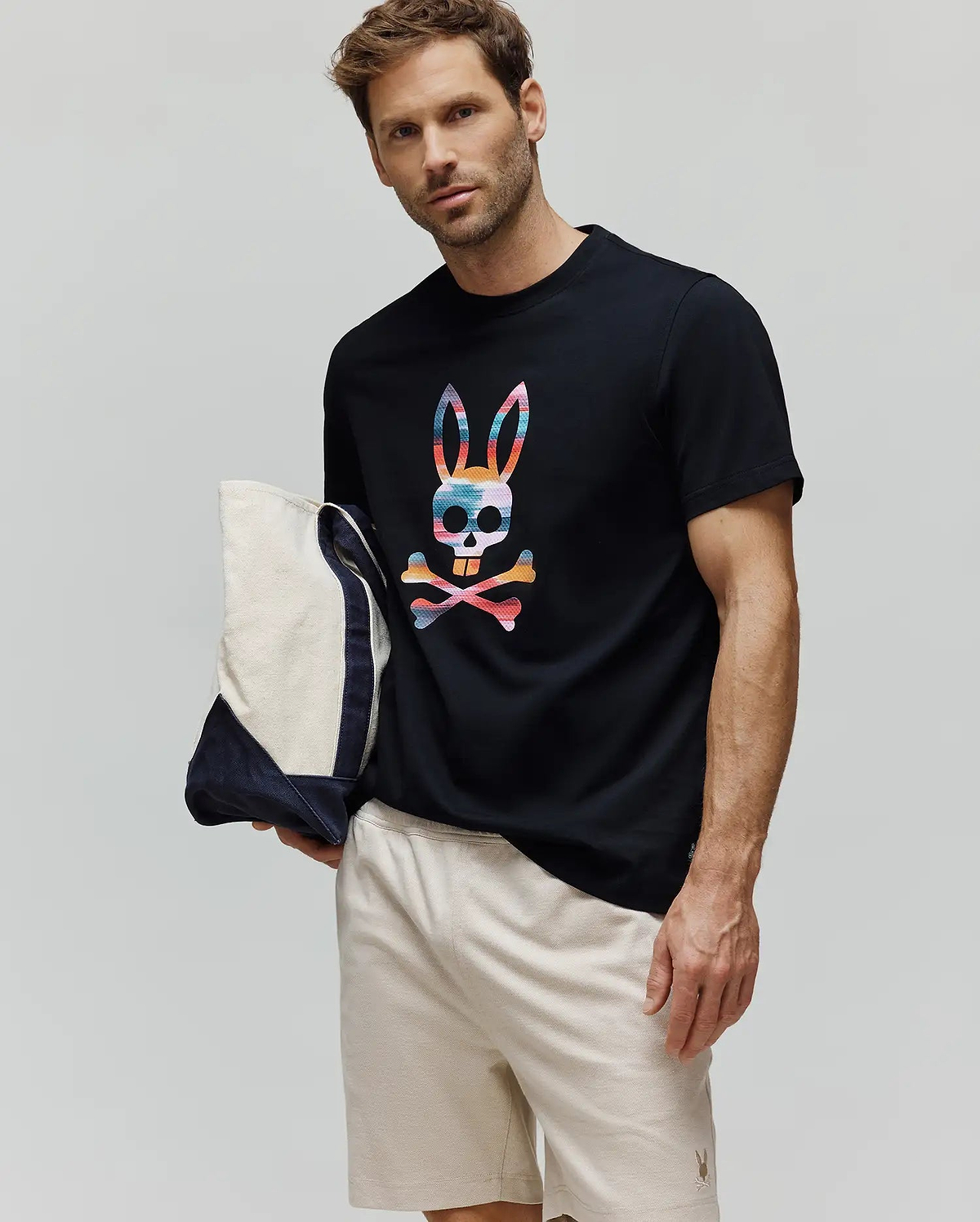 Mens Raphael Graphic Tee, a black classic-fit jersey t-shirt with a large multicolor bunny skull graphic on the chest, paired with light beige relaxed-fit pique shorts featuring a small embroidered bunny logo. (2)