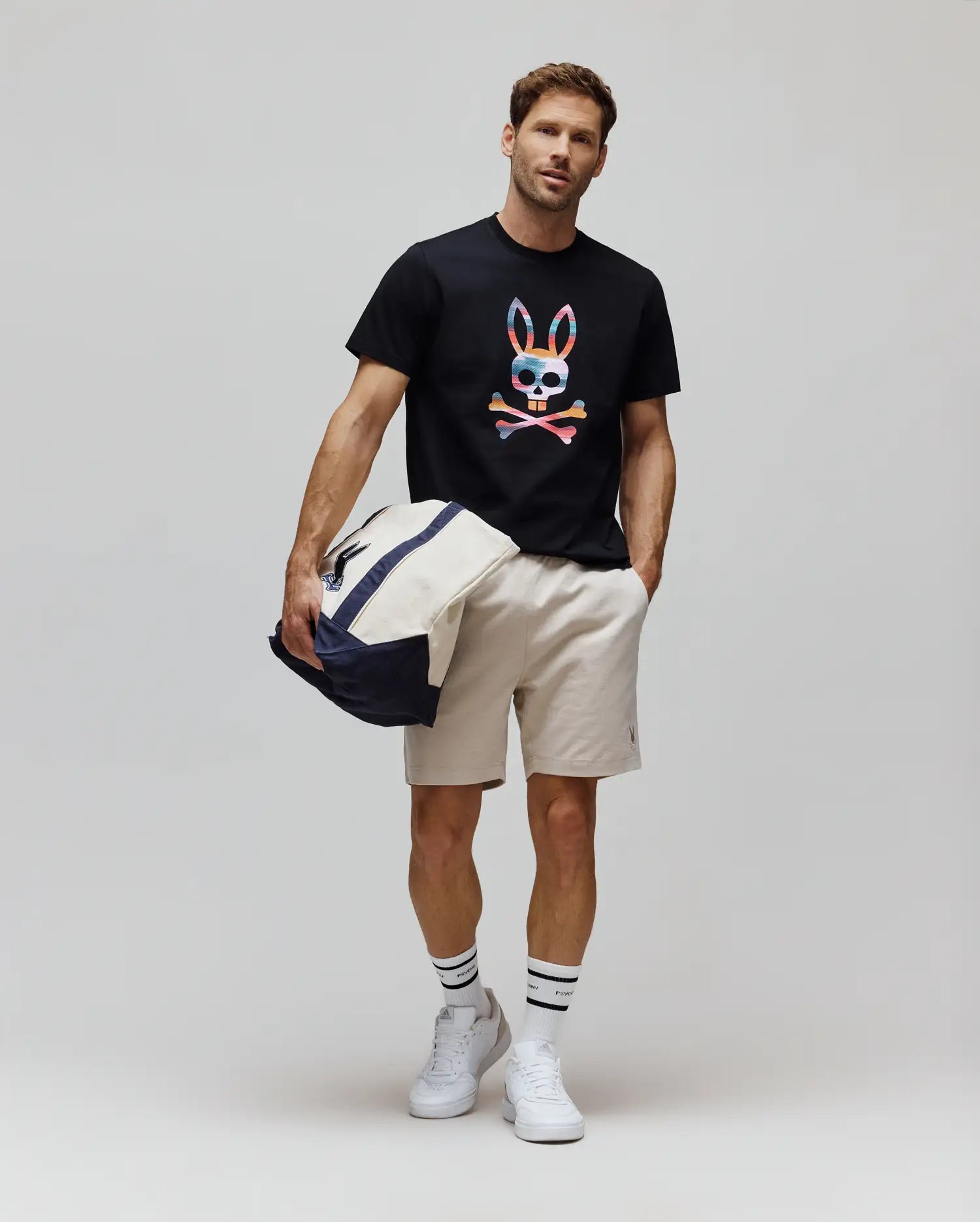 Black Mens Raphael Graphic Tee, a classic fit jersey t-shirt featuring a large, vibrant multicolor striped Psycho Bunny skull chest graphic, paired with beige woven shorts detailed with a small embroidered bunny logo. (5)