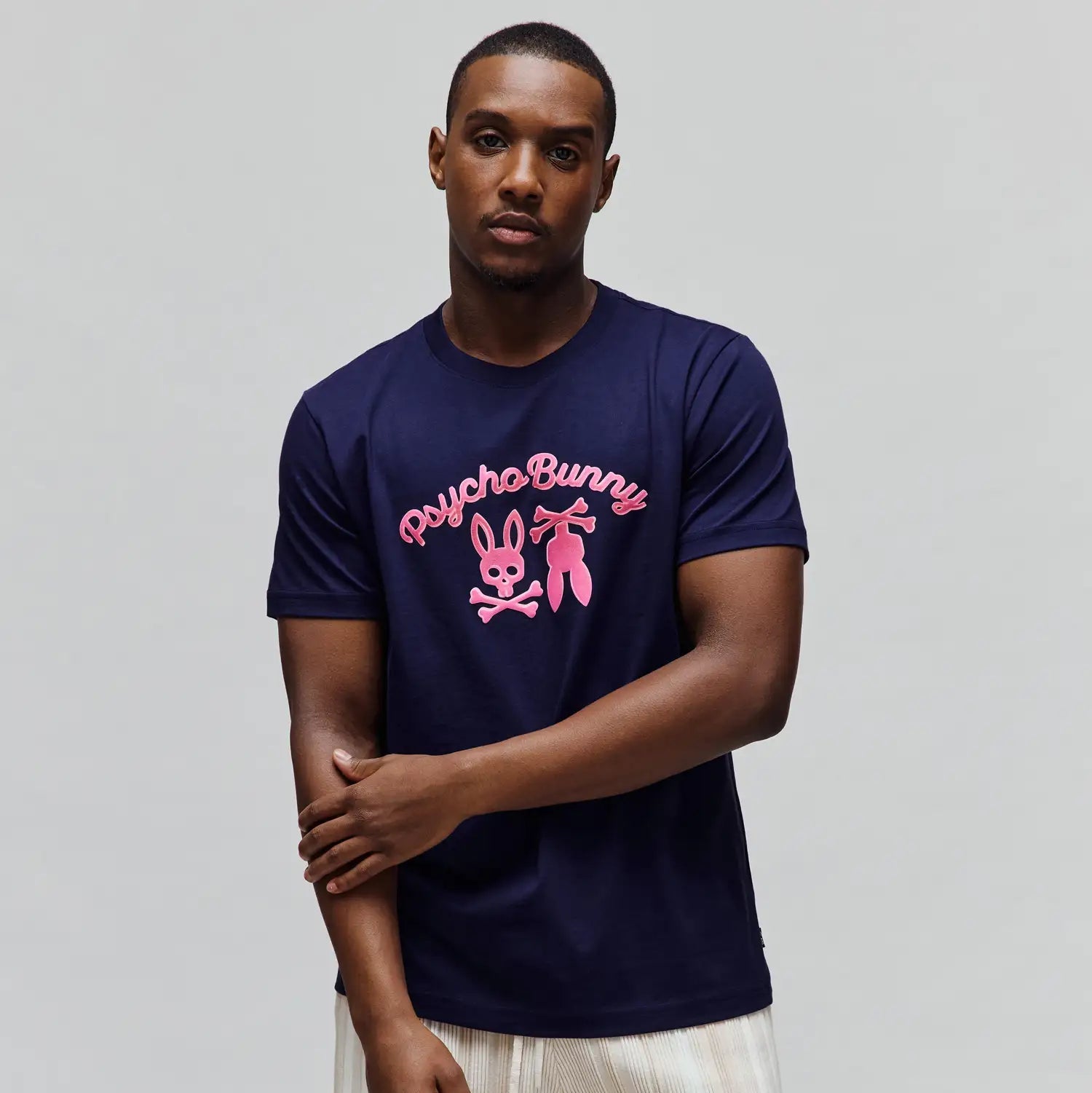 Mens Aram Graphic Tee, a navy blue classic fit smooth jersey knit t-shirt featuring a large hot pink Psycho Bunny script and bunny skull logo graphic on the chest. (2)