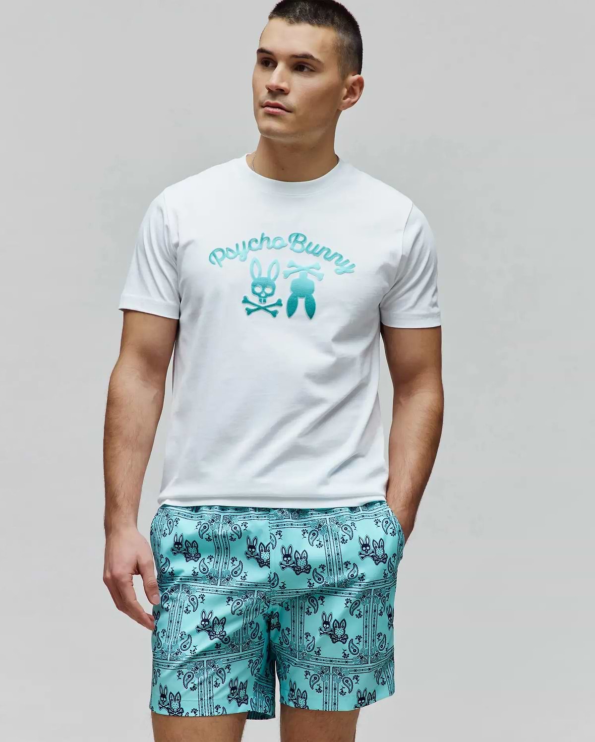 Mens Aram Graphic Tee in classic fit white jersey, featuring a large central chest graphic with Psycho Bunny script, the iconic bunny skull, and bunny tail elements in a vibrant teal gradient. (2)