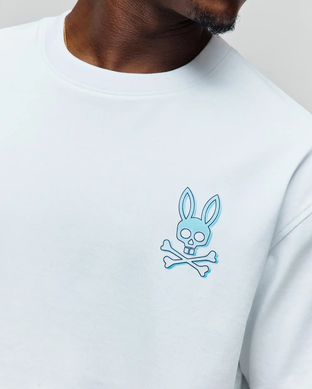 Mens Dax Oversized Tee, white smooth jersey knit, featuring a small embroidered light blue and dark blue outline Psycho Bunny skull and crossbones logo on the left chest. (2)