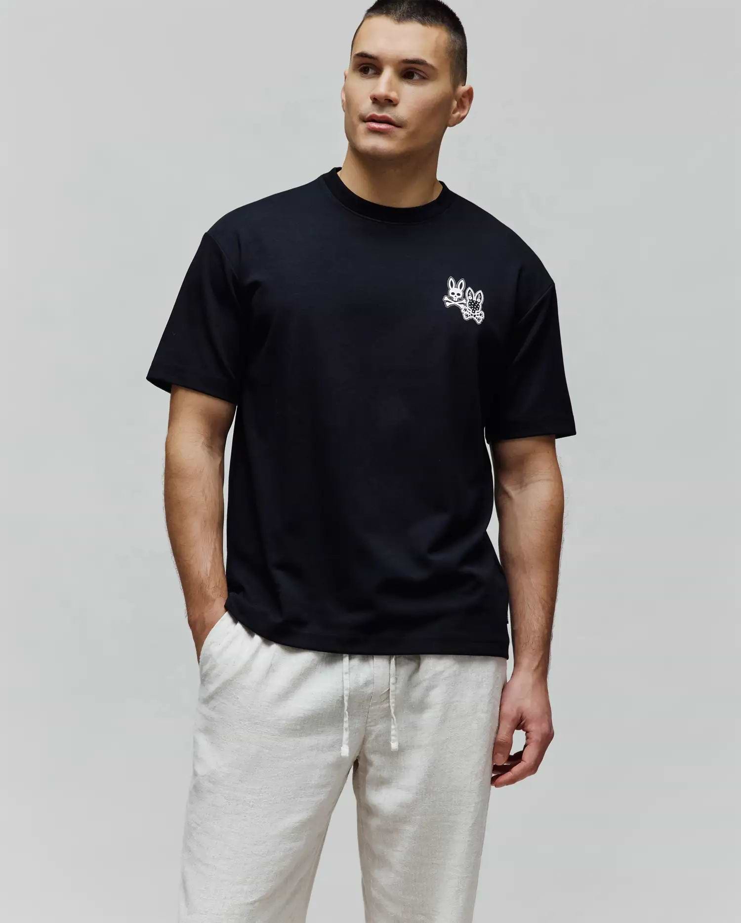 Black Mens Luke Back Graphic Tee, a relaxed fit jersey t-shirt with a small white embroidered Psycho Bunny double-bunny skull logo on the left chest and a graphic on the back.