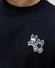 Black Mens Luke Back Graphic Tee in classic fit jersey knit, featuring two small white Psycho Bunny skull logos with crossbones on the left chest, one plain, one with floral patterns.