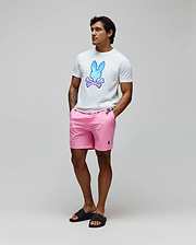 Mens Caspian Graphic Tee, a white classic fit jersey t-shirt with a large blue-pink gradient Psycho Bunny skull graphic on the chest, paired with pink woven shorts featuring a small embroidered black bunny logo.