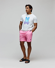 Mens Caspian Graphic Tee, a white classic fit jersey t-shirt with a large blue-pink gradient Psycho Bunny skull graphic on the chest, paired with pink woven shorts featuring a small embroidered black bunny logo.