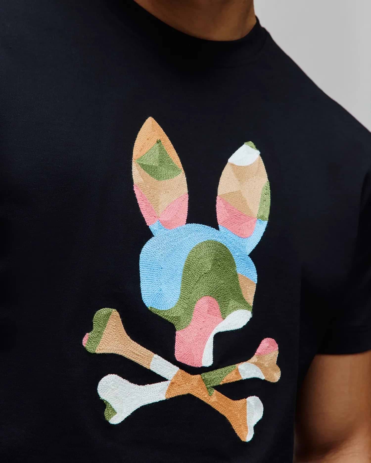 Mens Ara Graphic Tee, black classic fit jersey knit with a large, central multicolor geometric embroidered Psycho Bunny skull logo in pink, blue, green, beige, and white. (3)