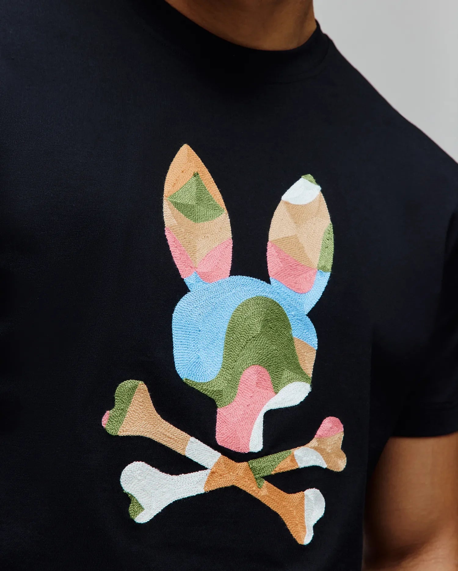 Mens Ara Graphic Tee, black classic fit jersey knit with a large, central multicolor geometric embroidered Psycho Bunny skull logo in pink, blue, green, beige, and white. (3)