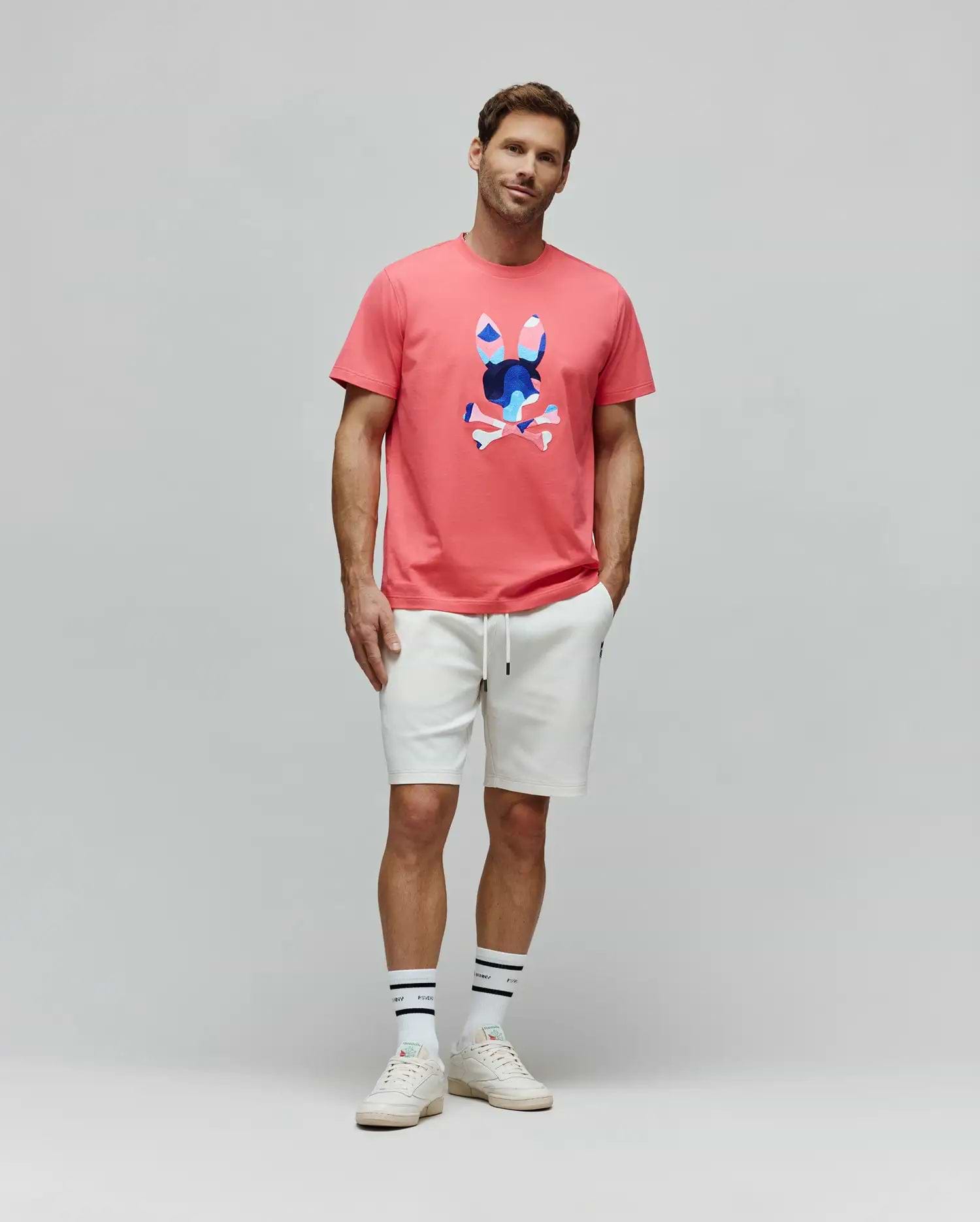 Mens Ara Graphic Tee in coral pink, a classic fit jersey with a large, center chest graphic bunny skull logo in blue, white, and pink abstract patterns. White relaxed fit french terry shorts. (5)