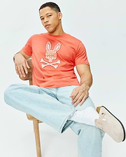 Mens Brad Graphic Tee in vibrant coral jersey knit, offering a classic fit and a prominent white Psycho Bunny skull and crossbones logo on the chest, detailed with an intricate palm tree pattern.