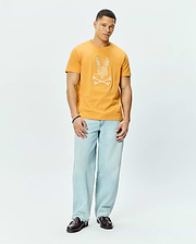Mens Brad Graphic Tee in mustard yellow, a classic fit soft jersey t-shirt featuring a large white patterned Psycho Bunny skull and crossbones graphic on the chest.