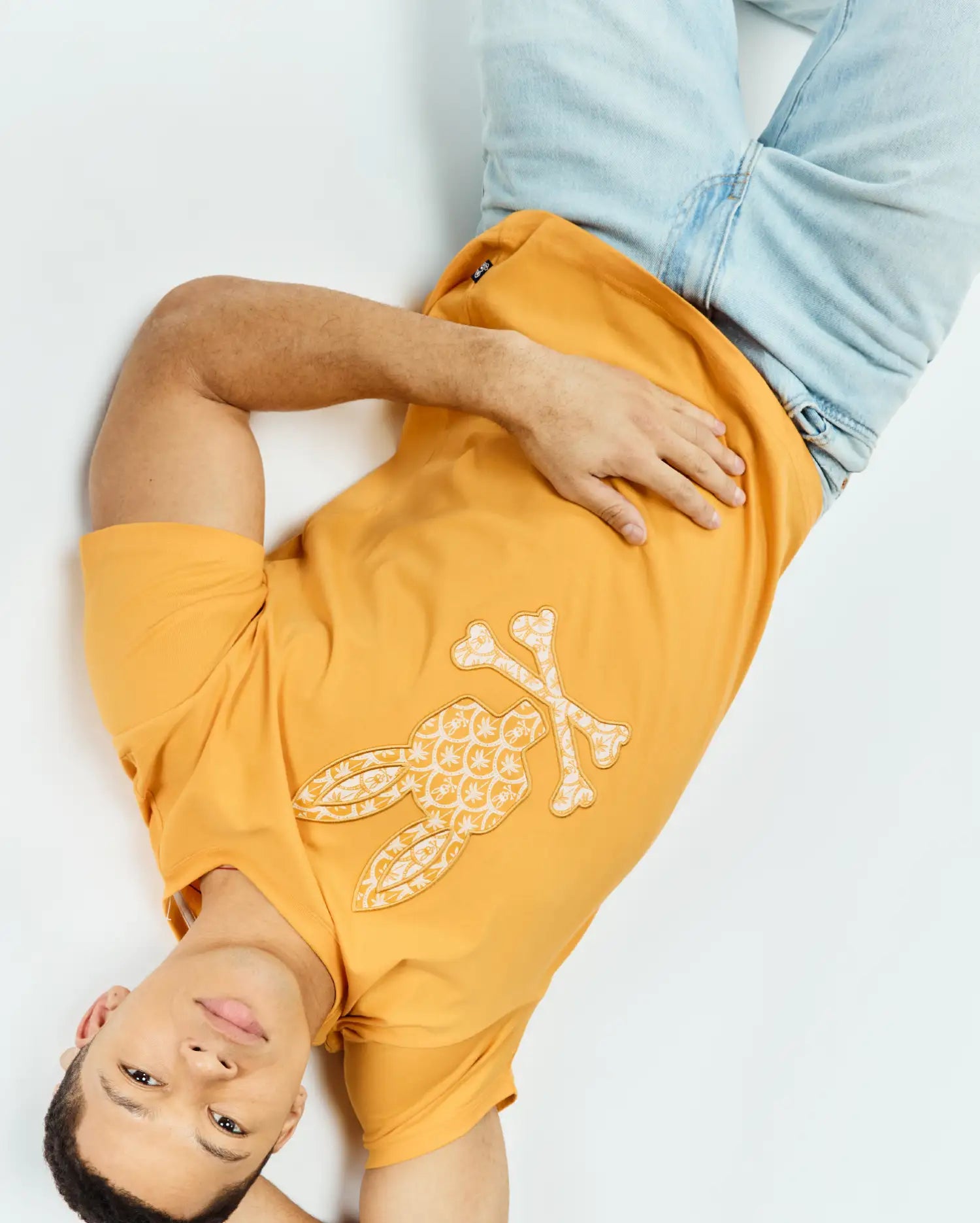 Marigold orange Mens Brad Graphic Tee, classic fit, smooth jersey knit, featuring a large cream and white Psycho Bunny skull logo graphic with intricate floral pattern on the chest.