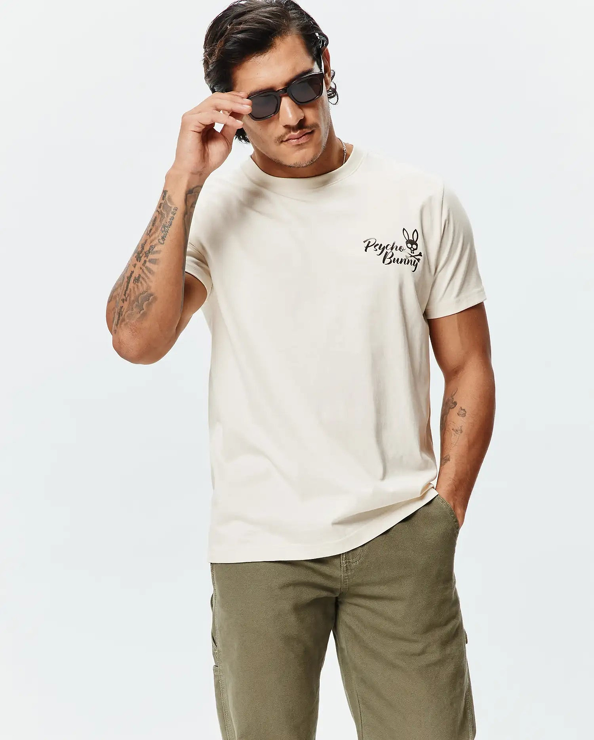 Mens Colin Back Graphic Tee, a premium soft cream jersey t-shirt with a classic fit, featuring a small embroidered black Psycho Bunny skull logo on the left chest.