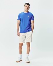 Mens Sunny Chest Graphic Tee and cream shorts. Blue jersey t-shirt with a classic fit, featuring a small embroidered Psycho Bunny skull logo with red eyes and sunglasses on the left chest. Cream relaxed fit shorts. (5)