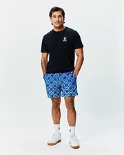Mens Sunny Chest Graphic Tee, a classic fit black jersey t-shirt with a small white embroidered Psycho Bunny skull logo on the left chest, paired with blue geometric print shorts and white crew socks. (2)