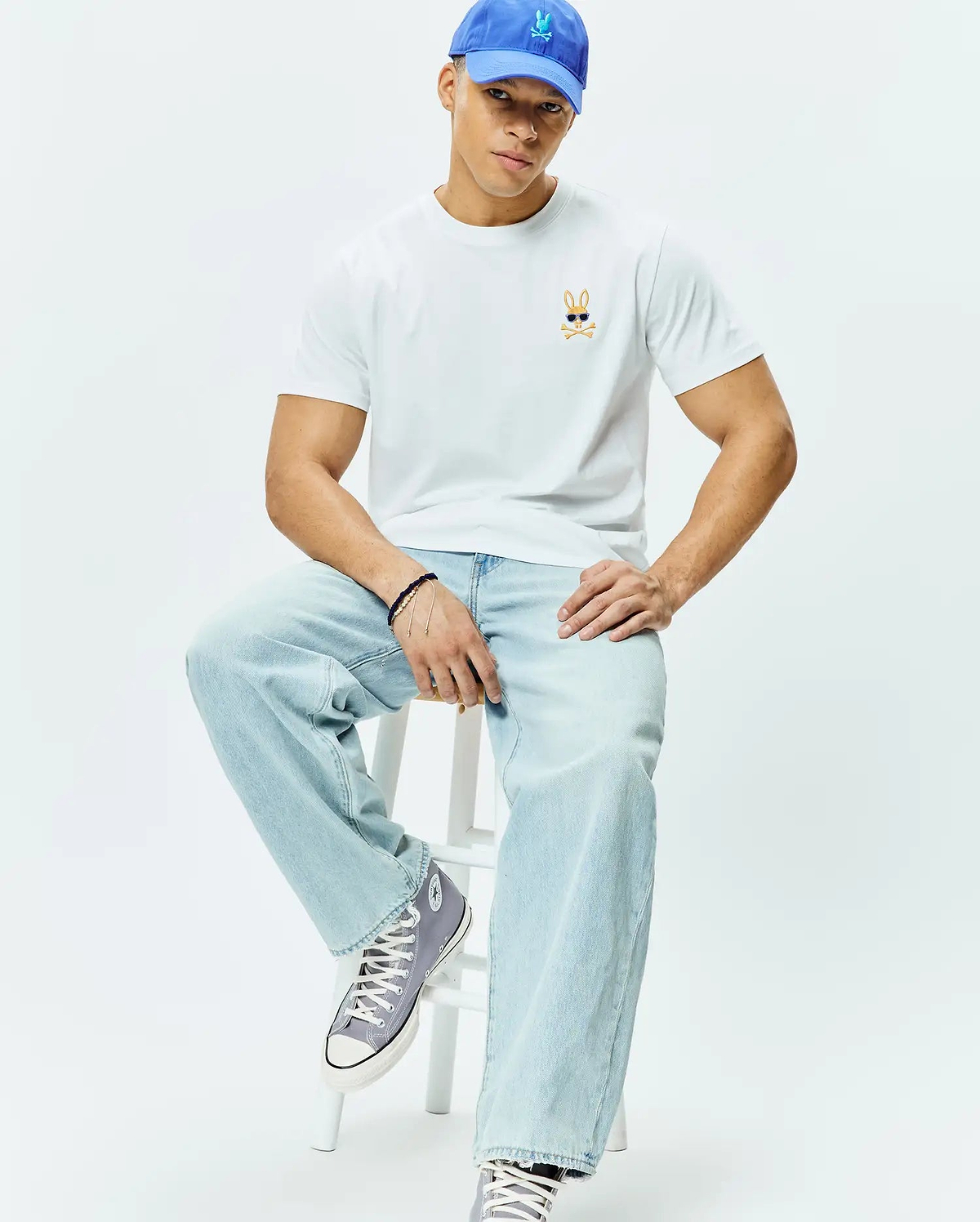 White Mens Sunny Chest Graphic Tee, classic fit, smooth jersey knit, featuring a small embroidered orange and black Psycho Bunny skull with blue sunglasses logo on the left chest.