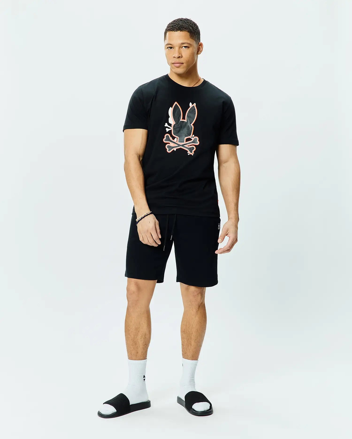 Black Mens Tanner Bunny Graphic Tee, classic fit jersey knit, with a large central orange-outlined bunny skull and crossbones graphic. Black relaxed fit knit shorts with drawstring and small embroidered bunny logo.