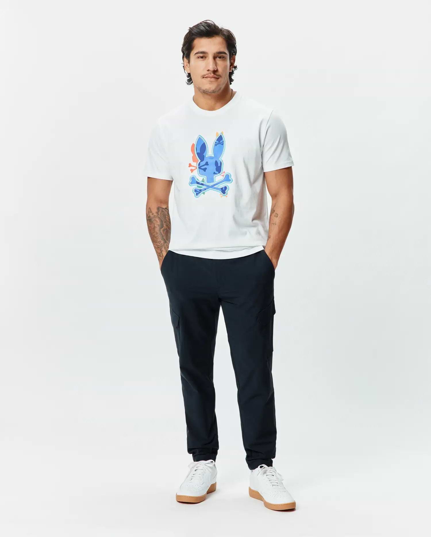Mens Tanner Bunny Graphic Tee, a classic fit white jersey t-shirt featuring a large, vibrant blue Psycho Bunny skull graphic with orange, yellow, and green accents on the chest, paired with slim navy joggers. (5)