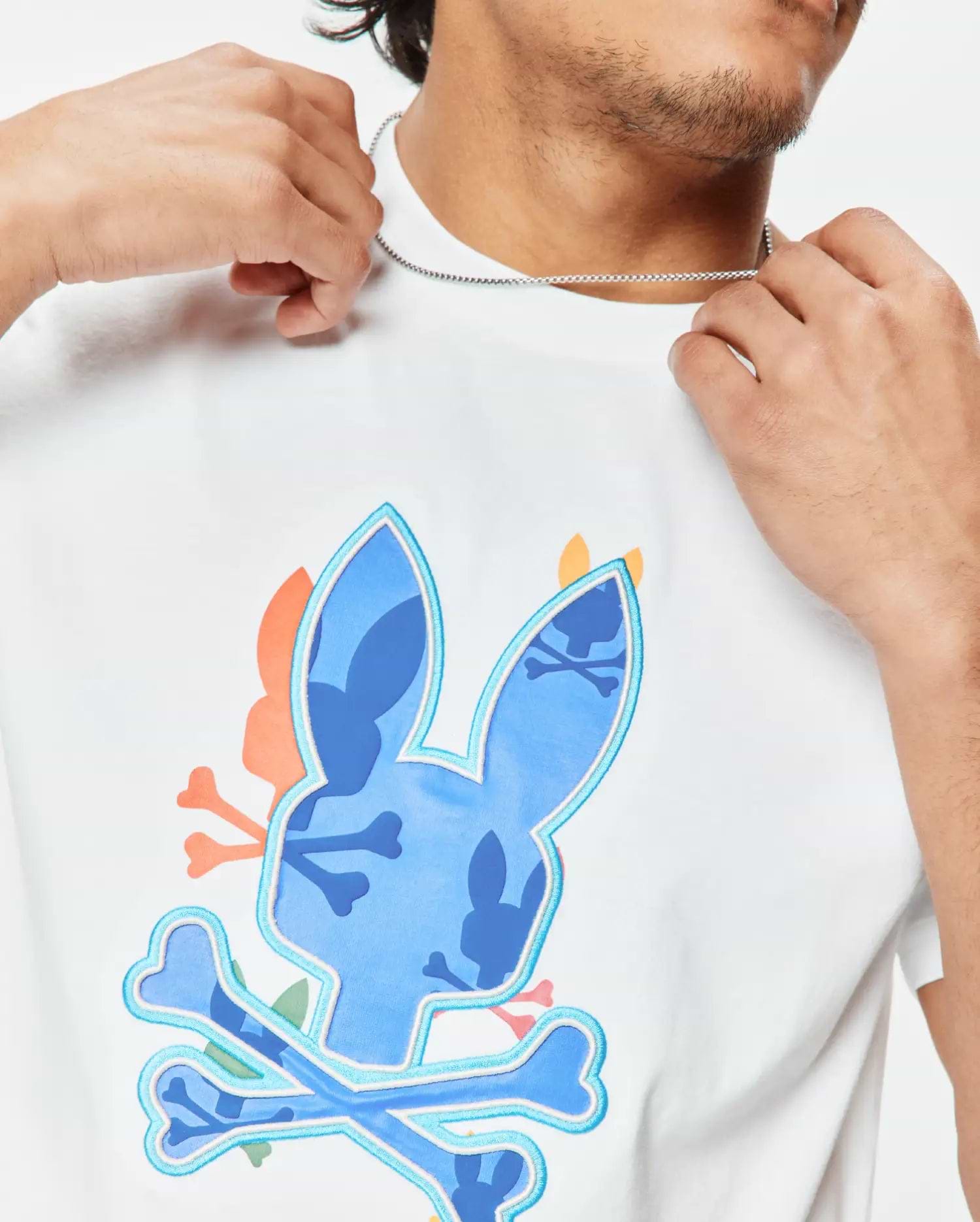 Mens Tanner Bunny Graphic Tee, a white classic fit jersey t-shirt featuring a large central blue camouflage bunny skull logo with light blue outline and crossed bones, accented with orange and pink details. (3)