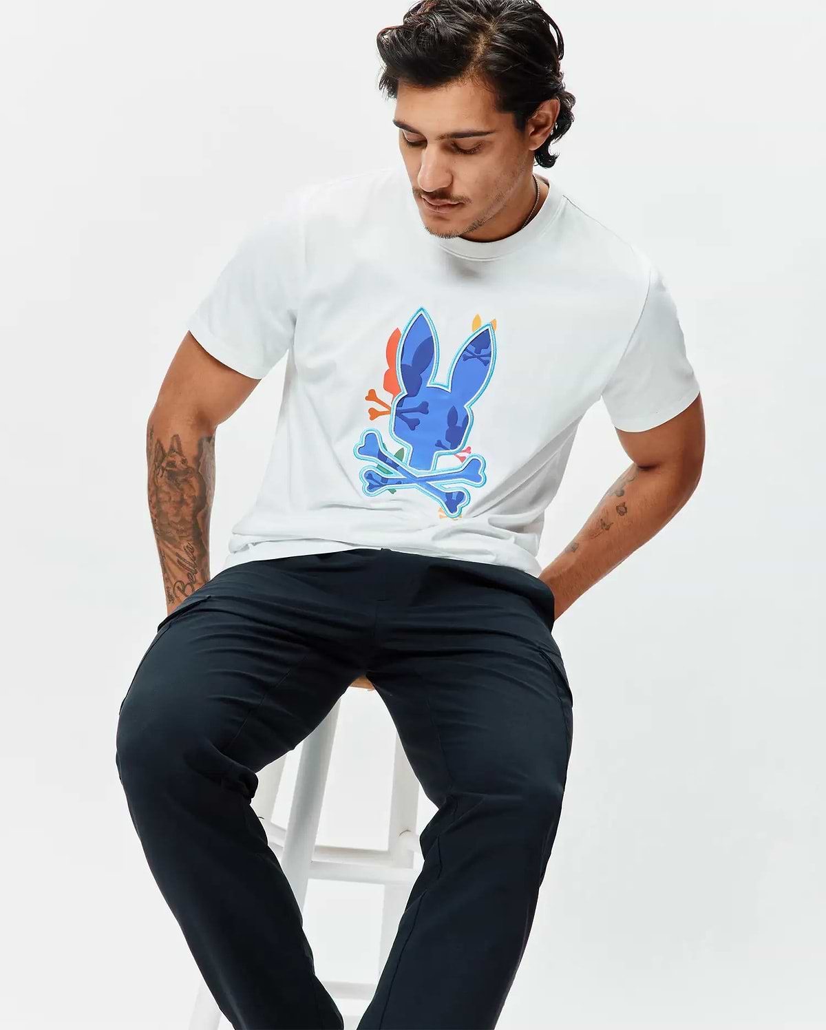 Mens Tanner Bunny Graphic Tee, a classic fit white jersey t-shirt featuring a large central blue Psycho Bunny skull and crossbones graphic with orange and light blue accents. (4)