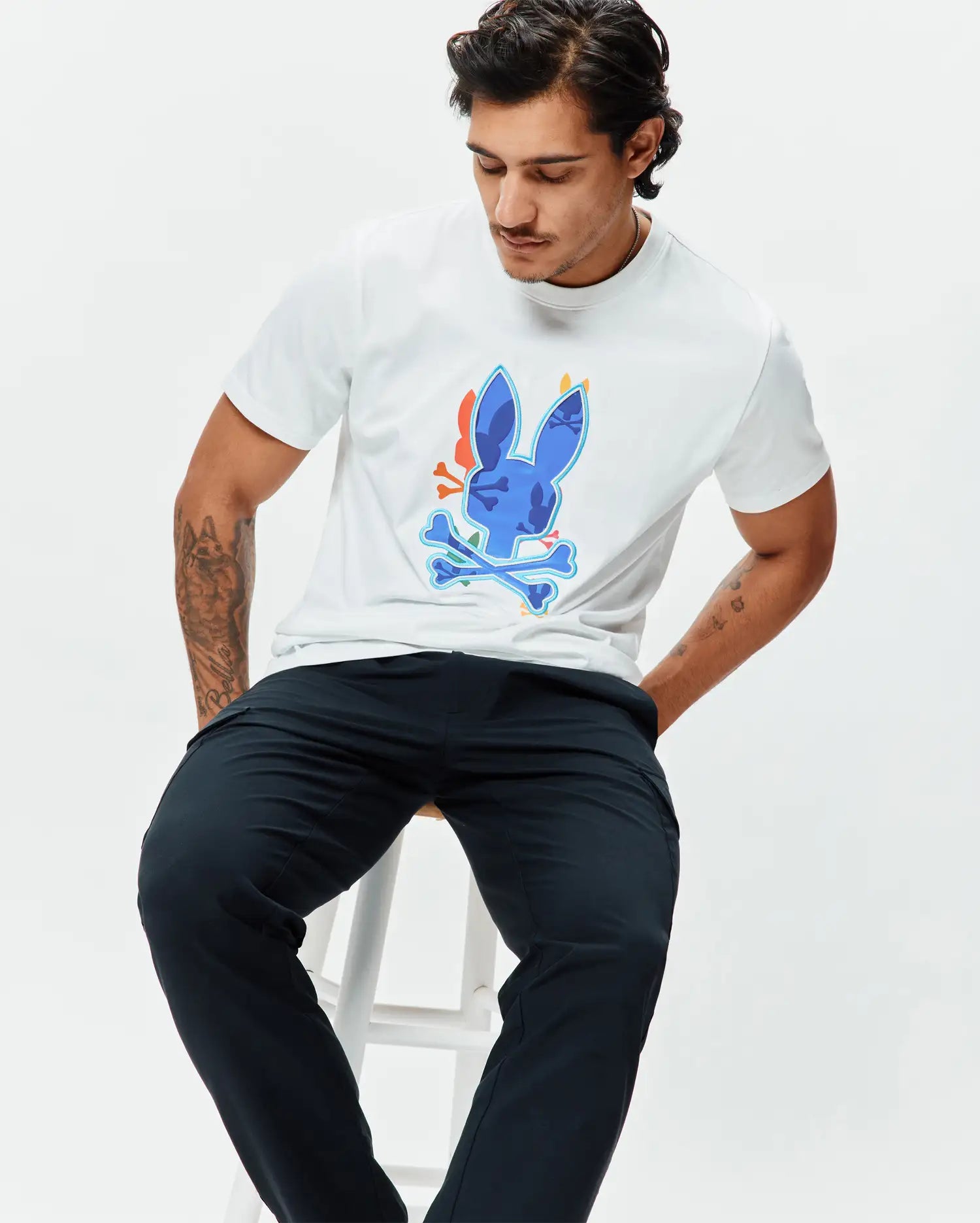 Mens Tanner Bunny Graphic Tee, a classic fit white jersey t-shirt featuring a large central blue Psycho Bunny skull and crossbones graphic with orange and light blue accents. (4)