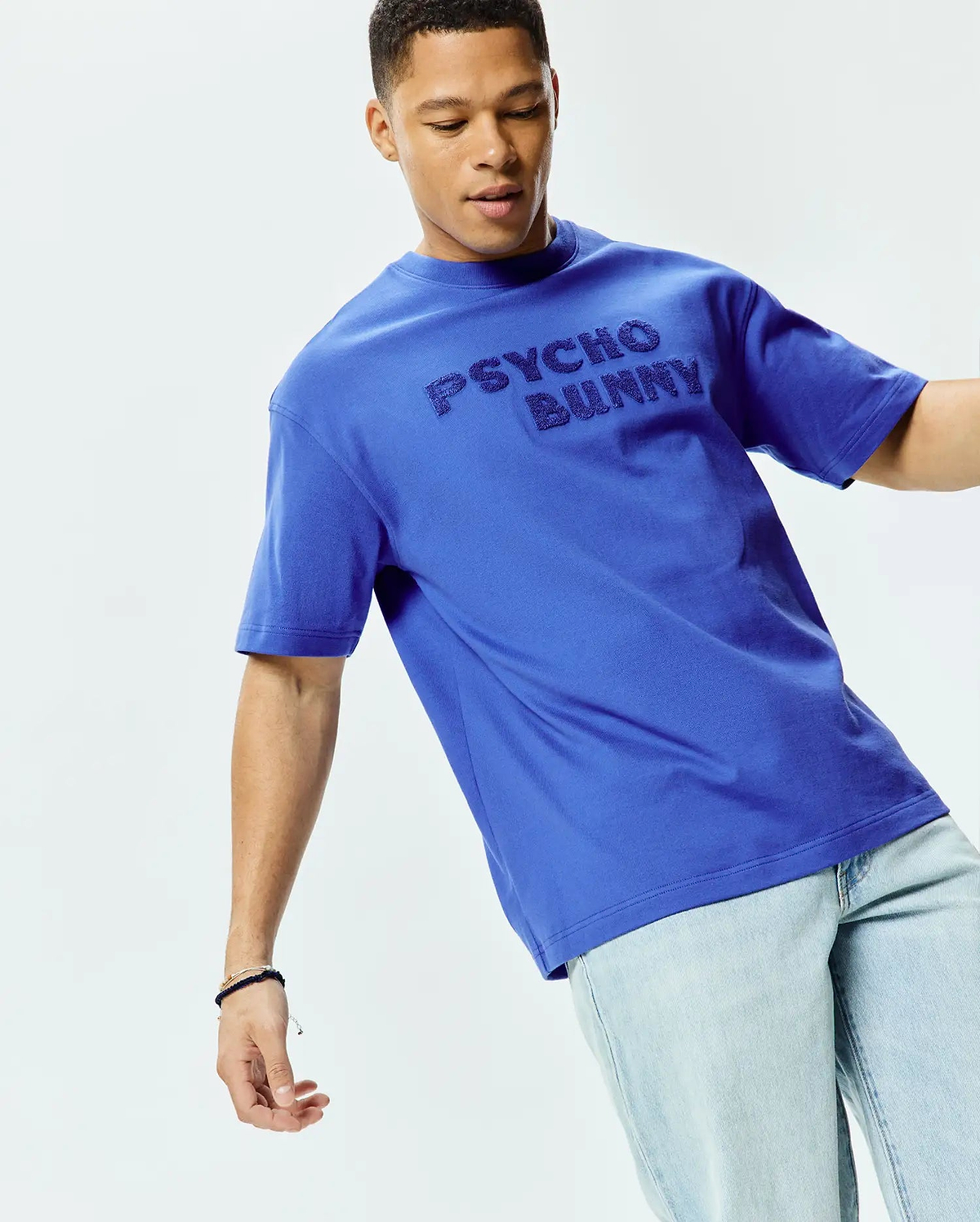 Mens Craig Wordmark Tee, a vibrant royal blue relaxed fit jersey t-shirt featuring a large, tonal embossed PSYCHO BUNNY wordmark across the chest. (3)