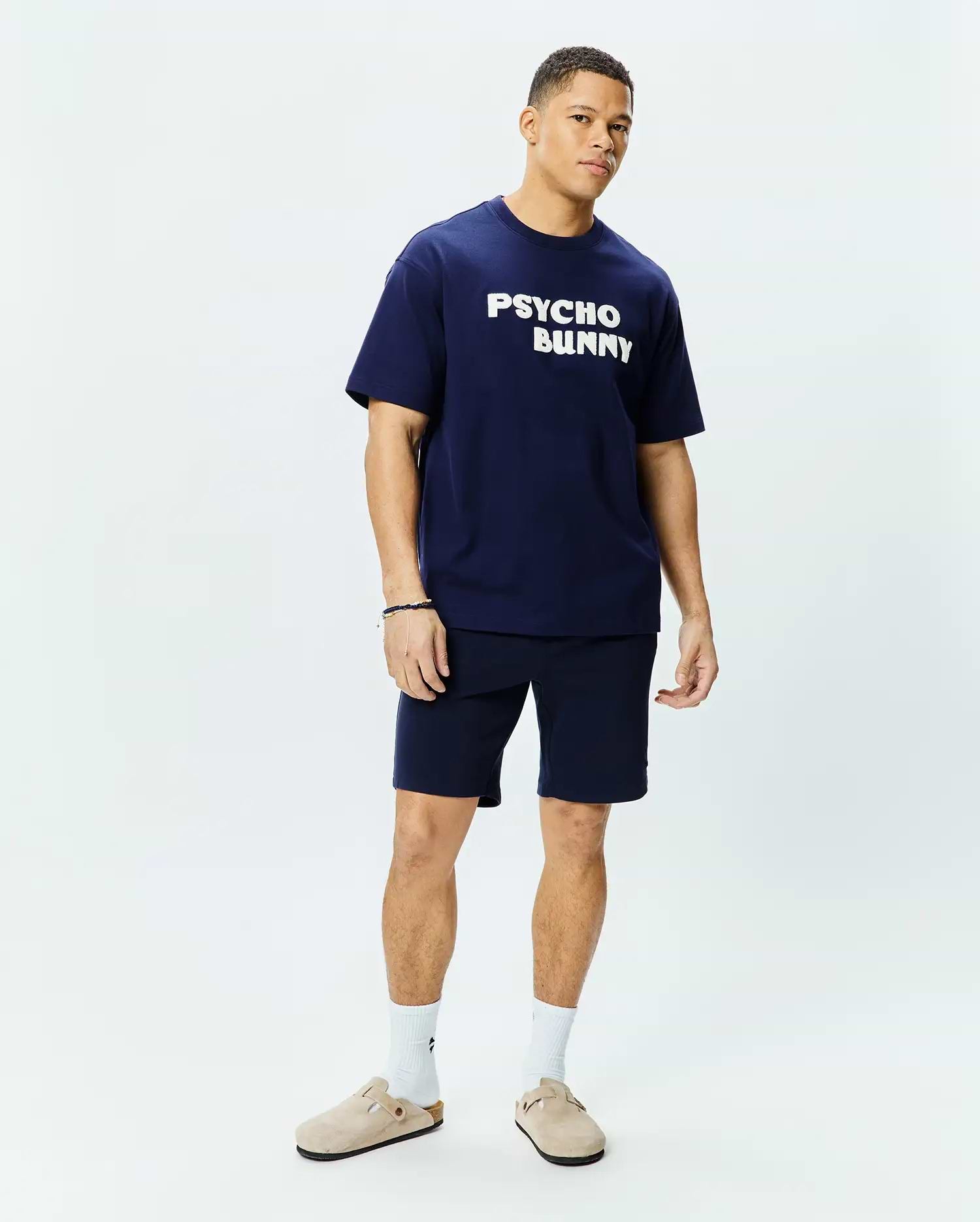 Mens Craig Wordmark Tee, a navy blue relaxed fit jersey tee with a large white PSYCHO BUNNY chest graphic, paired with matching navy knit shorts. (4)