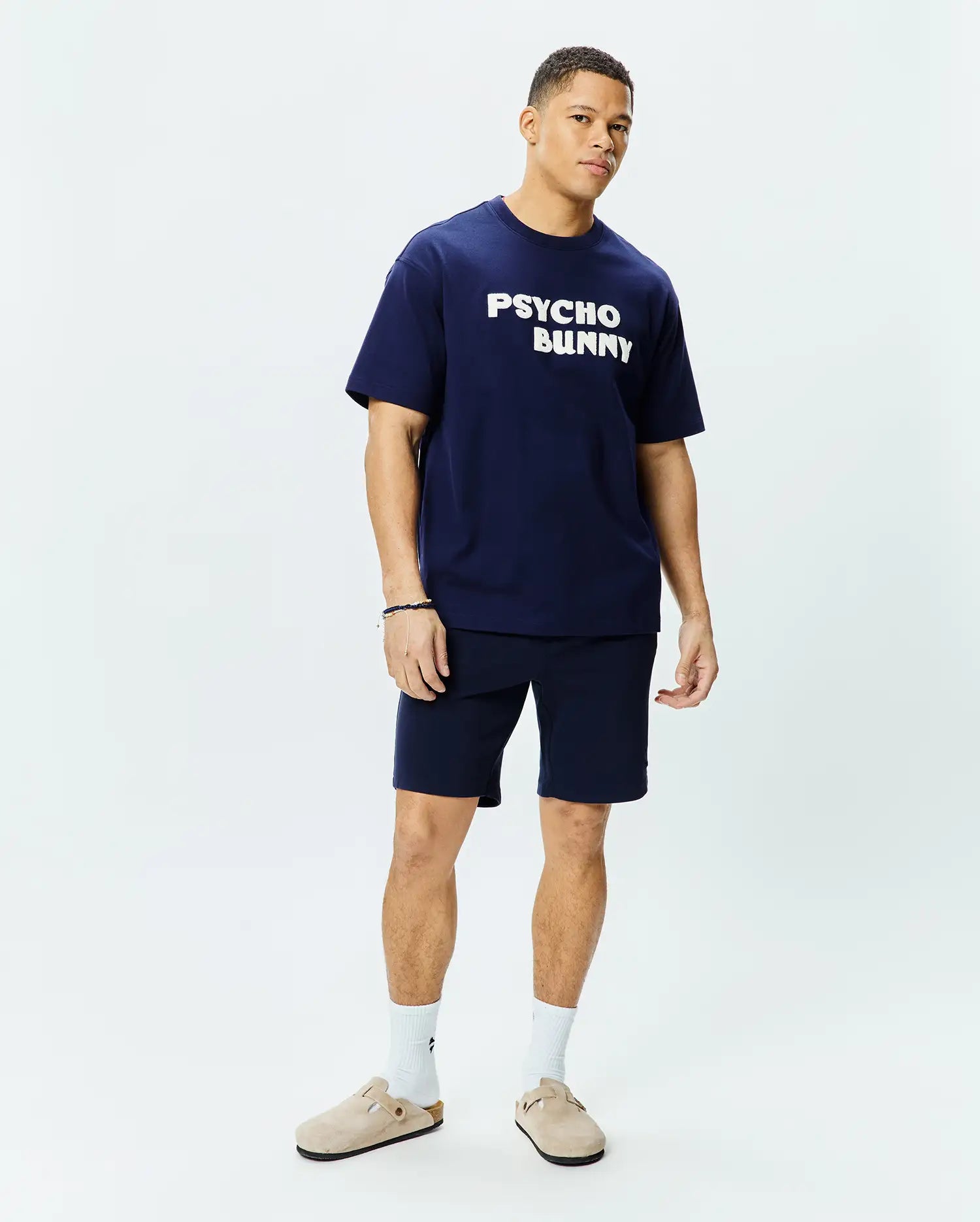 Mens Craig Wordmark Tee, a navy blue relaxed fit jersey tee with a large white PSYCHO BUNNY chest graphic, paired with matching navy knit shorts. (4)