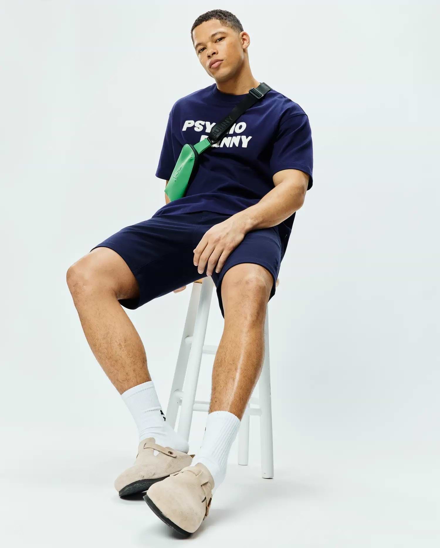 Navy blue Mens Craig Wordmark Tee, a relaxed-fit jersey t-shirt featuring a bold white Psycho Bunny chest wordmark, paired with matching navy jersey shorts. (3)
