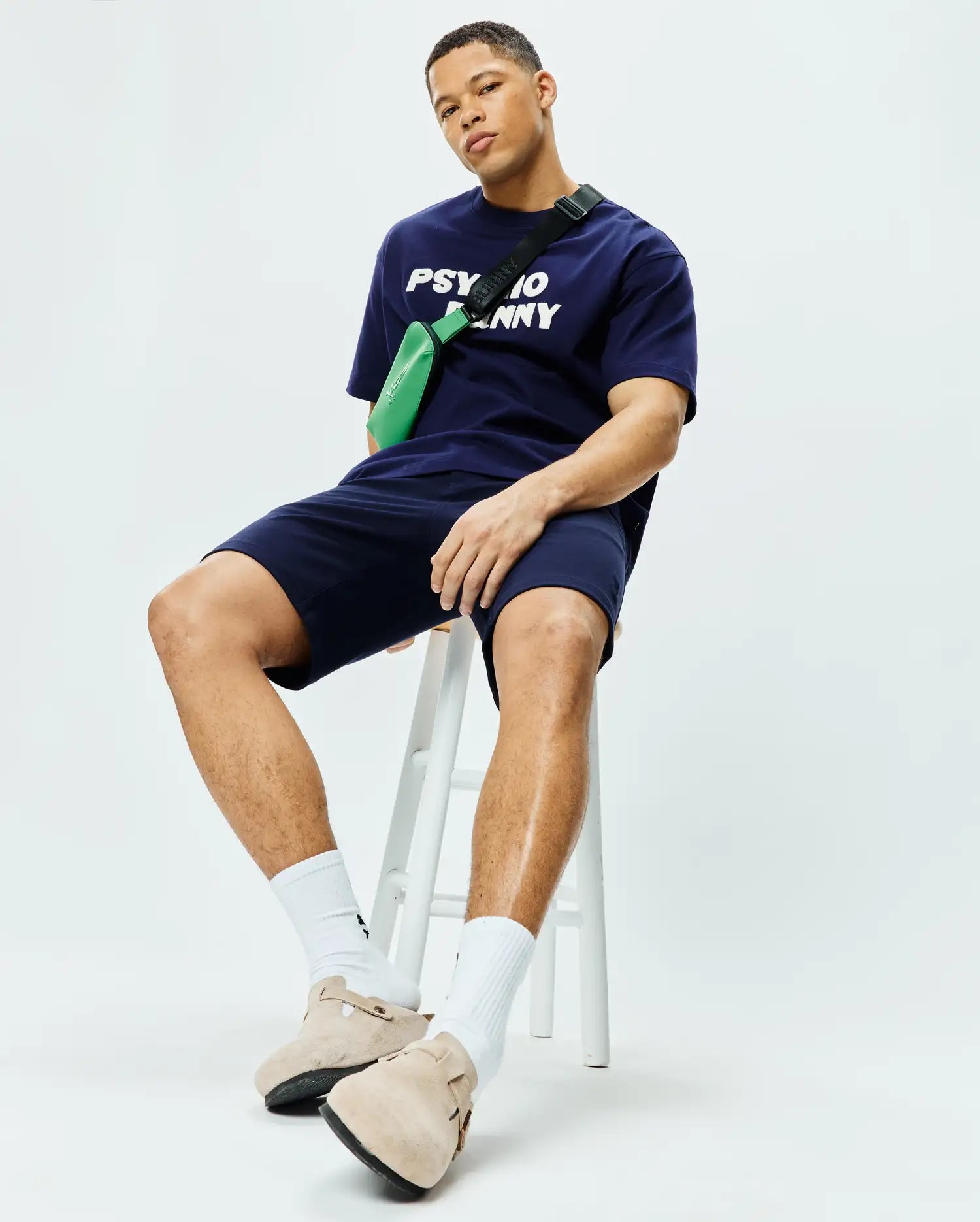 Navy blue Mens Craig Wordmark Tee, a relaxed-fit jersey t-shirt featuring a bold white Psycho Bunny chest wordmark, paired with matching navy jersey shorts. (3)