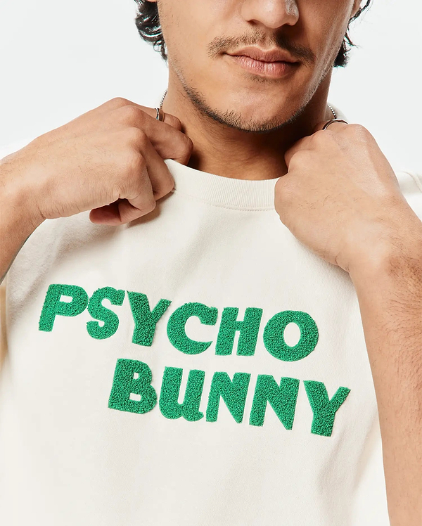 Mens Craig Wordmark Tee in premium cream jersey knit, showcasing a large, central bold green textured bouclé PSYCHO BUNNY wordmark embroidery for a classic streetwear fit.