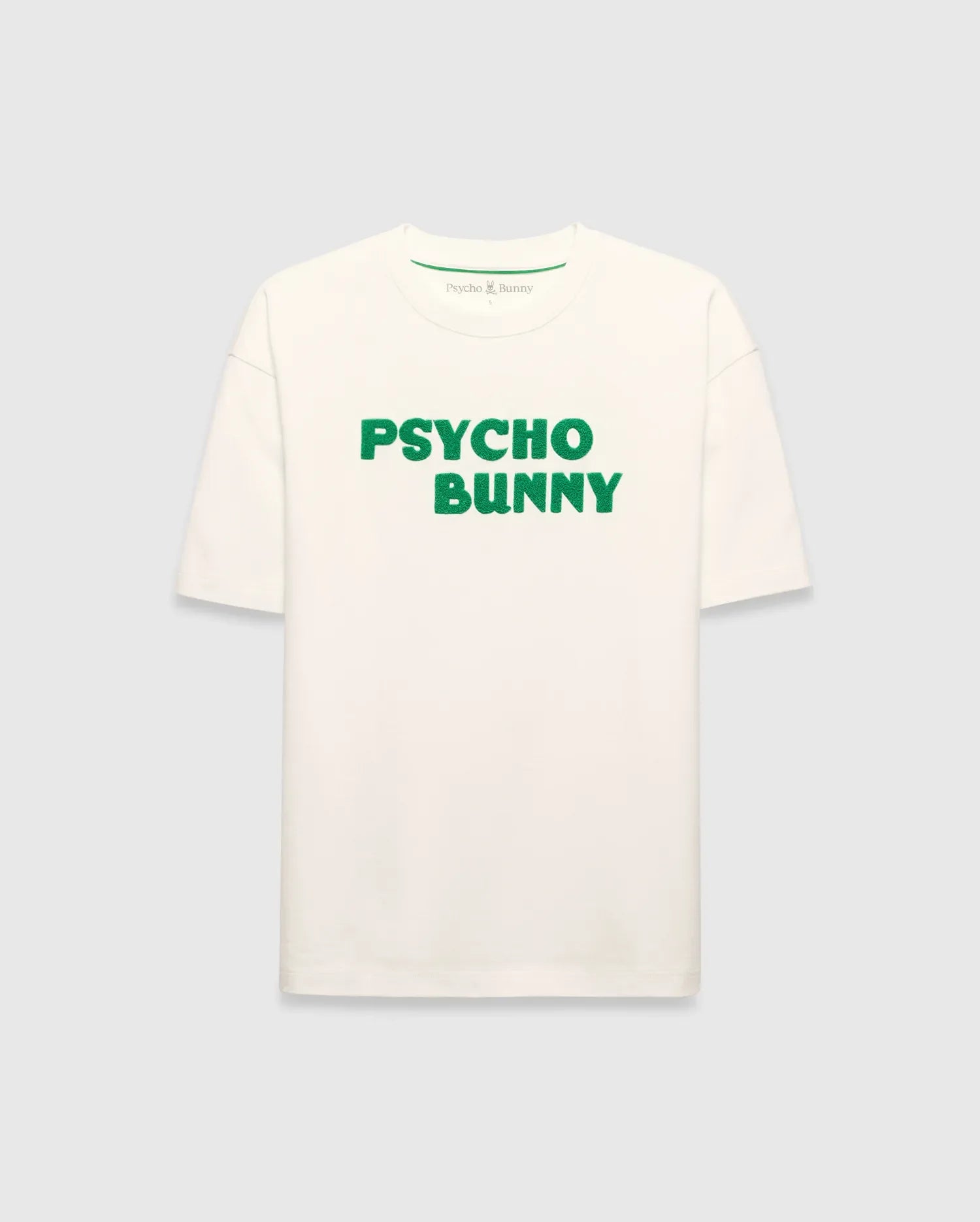 Mens Craig Wordmark Tee, a cream relaxed fit jersey t-shirt featuring a prominent green textured PSYCHO BUNNY wordmark graphic on the chest and a small green logo on the inner neck.