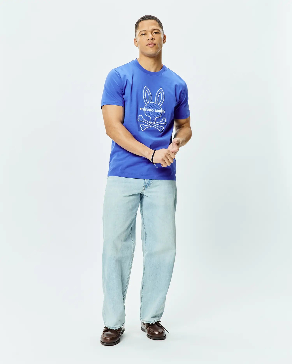 Mens Craig Graphic Tee, a royal blue classic fit jersey t-shirt featuring a large white Psycho Bunny skull and crossbones graphic logo centered on the chest. (4)