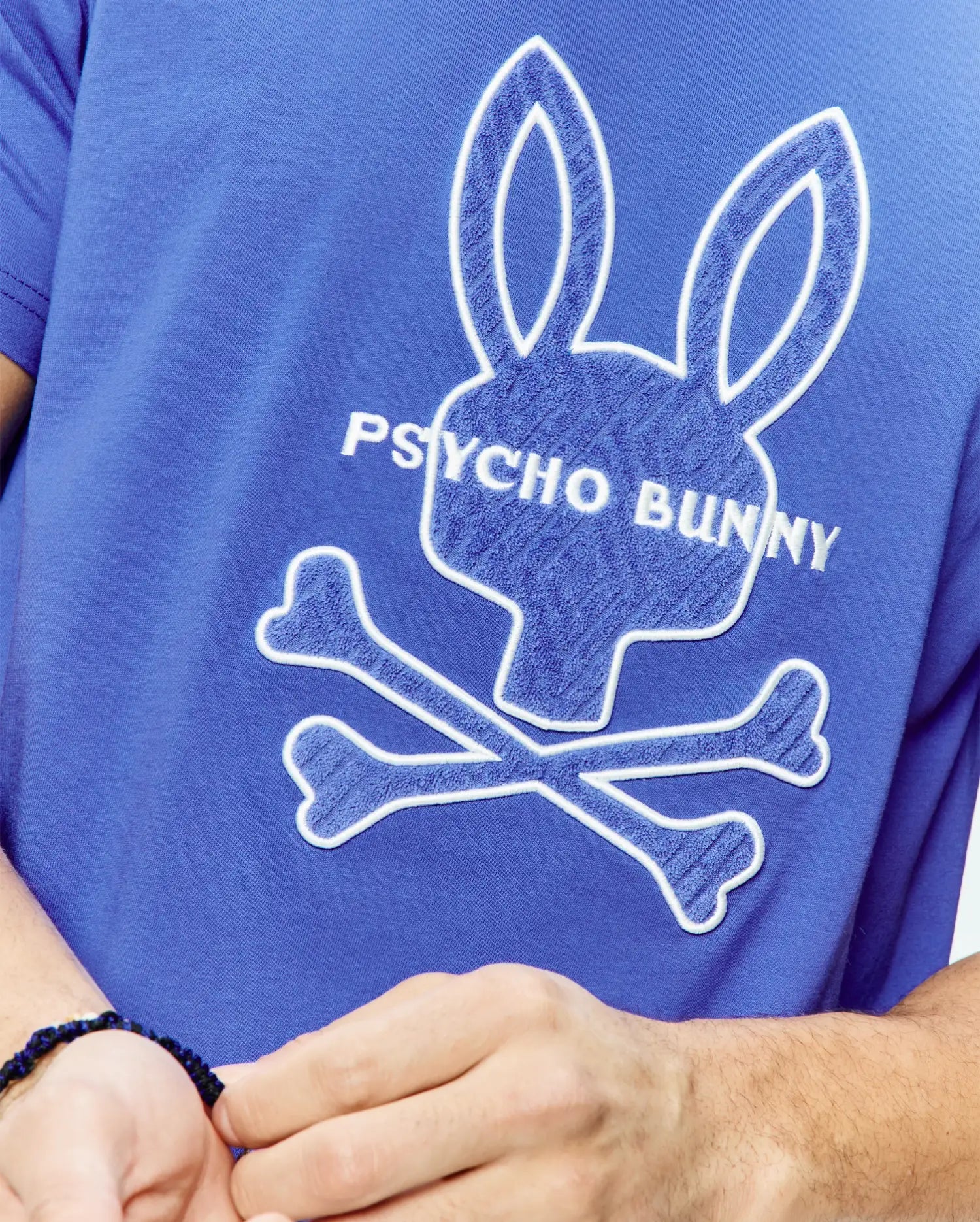 Mens Craig Graphic Tee in royal blue jersey knit, featuring a large white-outlined blue chenille Psycho Bunny skull graphic and embroidered Psycho Bunny text on the chest. (2)
